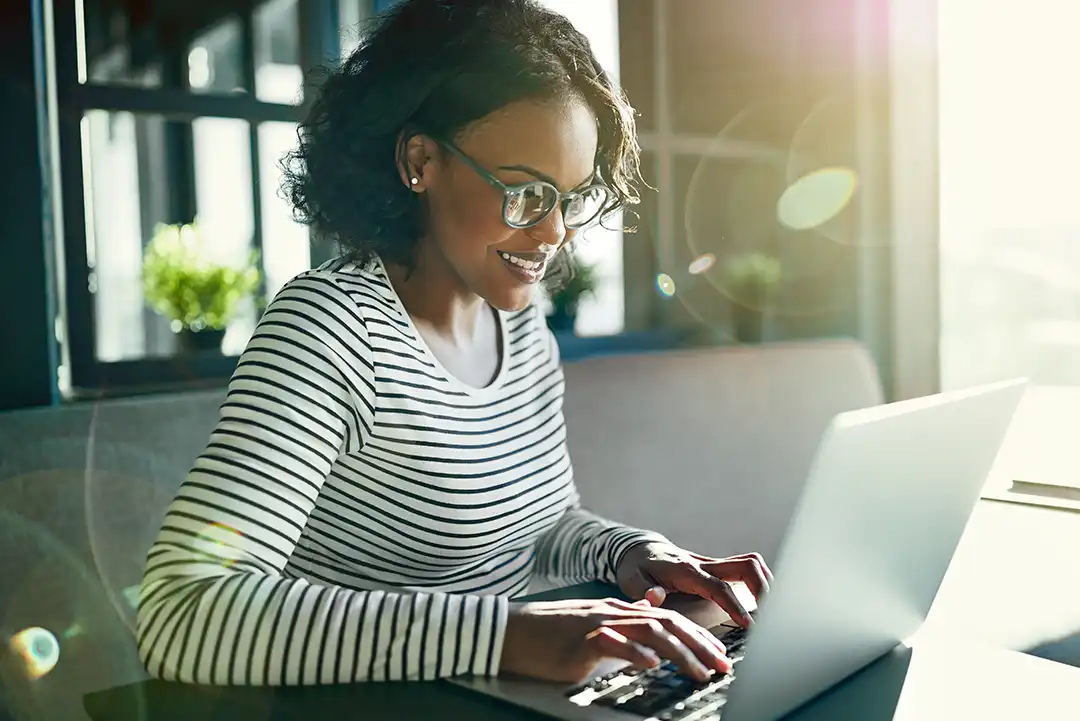Young African woman smiling and working online with a laptop